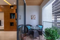 Balcony with wicker bistro set, teal cushions, flower wall art and wood-grain flooring, Hyderabad high-rise