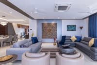 Spacious living room with two seating groups, carved wood feature panel and dining area beyond, marble floor, Hyderabad