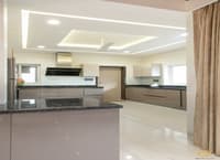 Modular kitchen in Hyderabad with taupe glossy cabinets, granite island, chimney hood and recessed cove ceiling