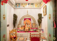 Home pooja room in Hyderabad with ornate silver mandap, deity idols, peacock feathers and pink draped offering table