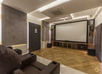 Home theatre in Hyderabad with projector screen, herringbone wood floor, leather recliners and grey textured panels