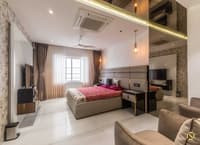 Bedroom in Hyderabad with grey channel headboard, floral feature walls, twin TVs and grey accent chairs