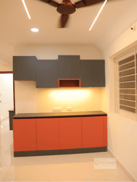 Modular crockery unit with grey overhead cabinets and burnt-orange base units under cove lighting, Hyderabad