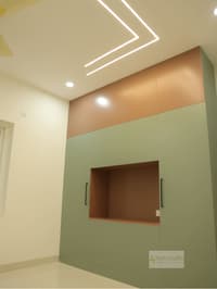 Sage-green storage cabinetry with terracotta top band, open display niche and chevron LED ceiling cove, Hyderabad