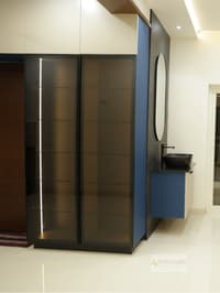 Foyer with frosted-glass sliding wardrobe, navy panel and wall-mounted vanity with oval mirror, Hyderabad