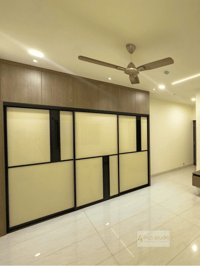 Sliding wardrobe with frosted-glass and black-framed panels under a wood loft and ceiling fan, Hyderabad