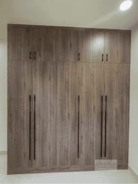 Full-height six-door wardrobe in grey-toned wood with slim black handles against a cream wall, Hyderabad