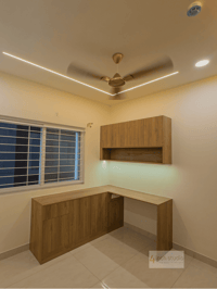 Study corner with L-shaped wood desk, wall-mounted shelf, window and cove-lit false ceiling, Hyderabad