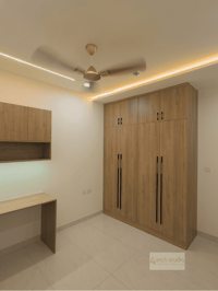 Bedroom study corner in Hyderabad with tall wood-laminate wardrobe, floating desk and cove-lit false ceiling on beige tiles
