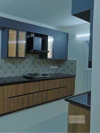 Modern kitchen with navy-blue cabinets, woodgrain base units, patterned Moroccan-tile backsplash and black countertop, Hyderabad