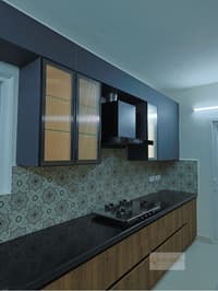 Kitchen with navy cabinets, fluted-glass shutters, black chimney and bold black-and-white Moroccan tile dado, Hyderabad