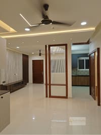 Foyer and living area with wood-finish wardrobe, framed glass partition door and false ceiling cove lighting, Hyderabad