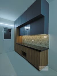 Kitchen crockery unit with navy wall cabinets, woodgrain base, black granite counter and ornate tile backsplash, Hyderabad