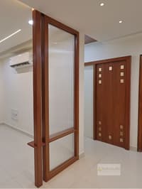 Foyer fluted-glass teak partition beside a panelled teak door with brass square inlays, Hyderabad home
