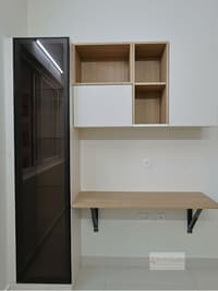 Study nook with wall-mounted wood desk, open shelves with sliding box and tall tinted-glass cabinet, Hyderabad apartment