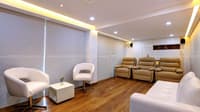 Home theatre lounge with tan leather recliners, white tub chairs and wood flooring under cove lighting, Hyderabad
