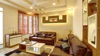 Living room with brown leather sofa set, lit wood wall niche, shag rug and glass display cabinet, Hyderabad