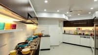 Spacious L-shaped kitchen in Hyderabad with white cabinets, walnut overheads, gas hob and recessed-lit false ceiling