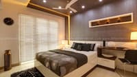 Master bedroom with textured headboard wall, gold cove-lit false ceiling, lit niche shelf and built-in study desk, Hyderabad