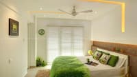 Bright bedroom with green leaf-print bedding, cork upholstered headboard, venetian blinds and yellow-lit false ceiling, Hyderabad
