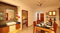 Dining area with stone-clad washbasin counter, six-seater wood table set and open doorway to bedroom, Hyderabad