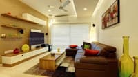 Compact living room with brown leather L-sofa, slim TV unit, floating shelves and shaggy rug, Hyderabad