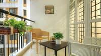 Compact balcony sitting area with yellow chair, potted greenery and black side table by grid glass doors, Hyderabad