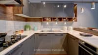 U-shaped modular kitchen with grey gloss cabinets, wood open shelving, white quartz counters and integrated sink, Hyderabad