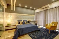 Contemporary bedroom with cushioned grey headboard wall, blue-grey bedding and mustard accent chair, Hyderabad
