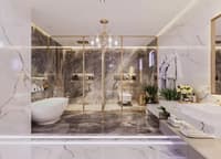 Grey-and-white marble bathroom with freestanding tub, glass shower, gold-framed WC and crystal chandelier, Hyderabad