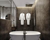 Dark stone bathroom with freestanding tub, rain shower, round mirror and twin white robes, Hyderabad