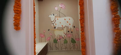 Pooja room with a hand-painted Pichwai-style cow and calf among lotus flowers, framed by marigold garlands, Hyderabad