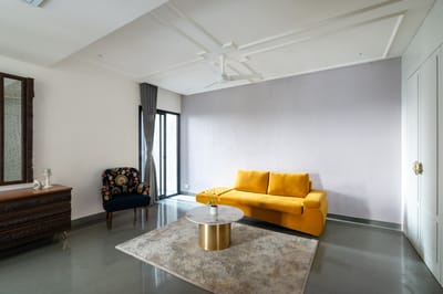Drawing room with a mustard-yellow sofa, navy floral chair, round marble-top table and polished concrete floor, Hyderabad