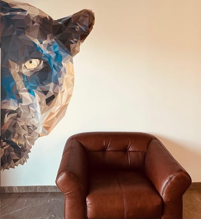 Hand-painted low-poly panther mural in blue and grey tones beside a brown leather armchair, Hyderabad