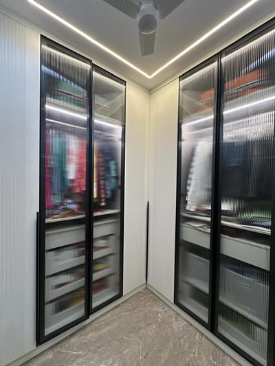 Walk-in wardrobe with black-framed fluted glass doors, LED cove lighting and pull-out drawers, Hyderabad