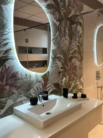 Modern bathroom in Hyderabad with tropical botanical wallpaper, backlit oval mirror and white vessel basin on stone vanity