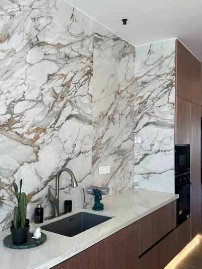 Kitchen corner in Hyderabad featuring veined Calacatta marble backsplash, walnut cabinetry and a stainless pull-out faucet over an undermount sink