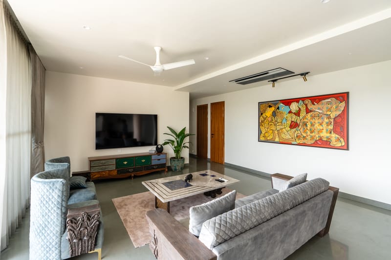Living room with wall-mounted TV, hand-painted console, grey tufted sofas and a vivid red abstract artwork, Hyderabad