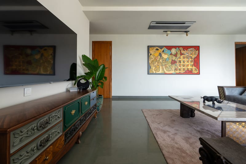 Living room with carved painted console, bold abstract artwork, leather and grey seating around a low marble table, Hyderabad