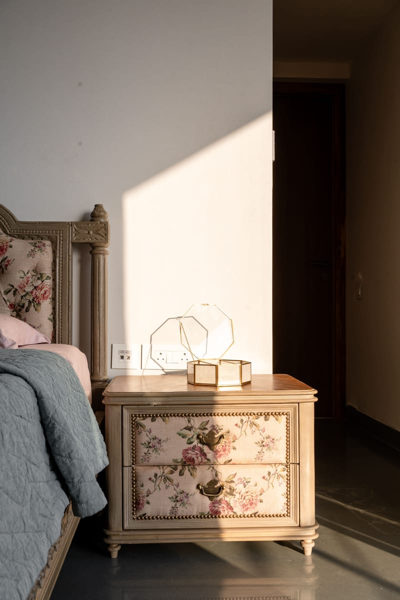 Bedside table in a Hyderabad bedroom with floral upholstered drawers, brass ring pulls and a geometric glass lamp in warm light