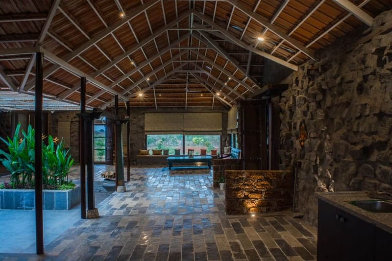 Spacious living hall with vaulted bamboo-and-timber ceiling, rough stone wall and reclaimed brick flooring, Hyderabad farmhouse