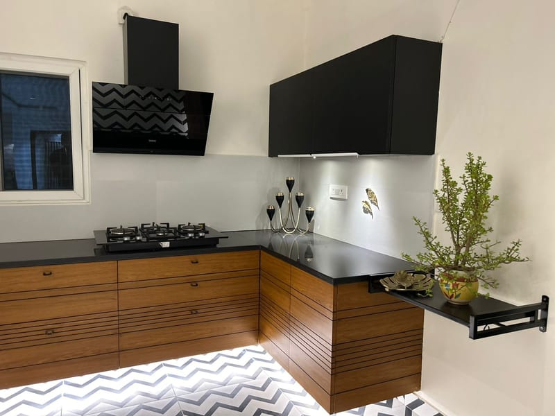Kitchen detail with walnut cabinetry, black upper units, a black-stone counter and a jade plant by the chimney, Hyderabad
