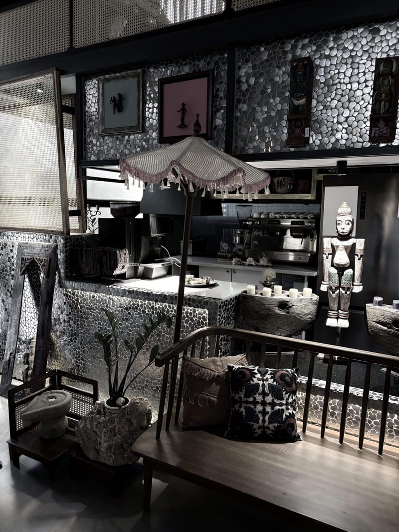 Dark eclectic lounge with pebble-mosaic walls, a fringed parasol lamp, carved figurines and a cushioned bench, Hyderabad
