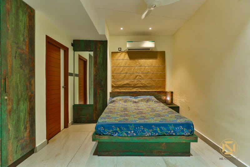 Bedroom with reclaimed green-finish bed and wardrobe, gold padded headboard and tile flooring, Hyderabad