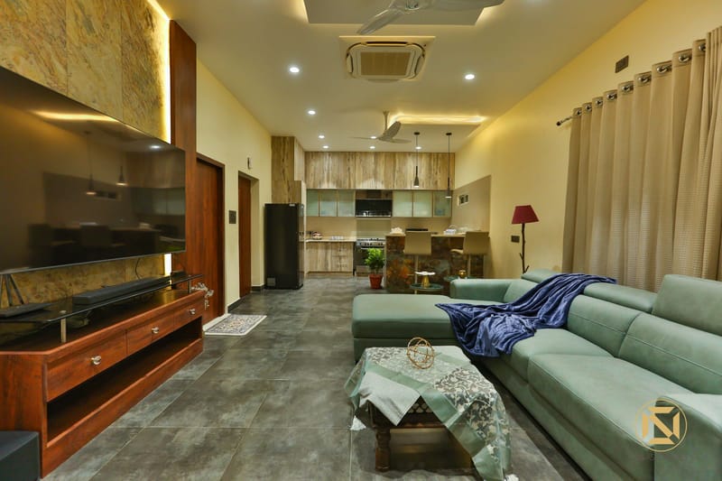 Living room with wood TV console, marble feature wall and teal sectional, kitchen and dining beyond, Hyderabad full home