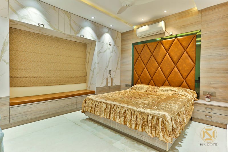 Master bedroom with quilted tan leather headboard, marble-effect TV wall and golden bedspread, Hyderabad home