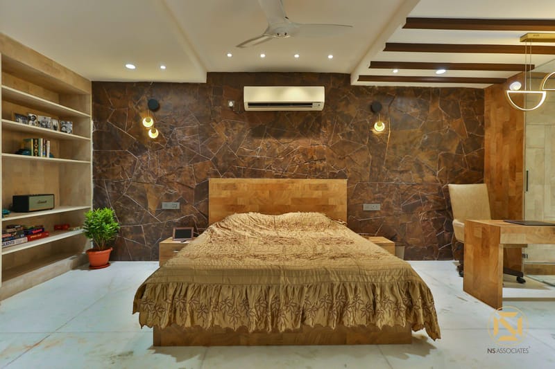 Bedroom with brown stone feature wall, wooden bed, hanging pendant lights and recessed niche shelving