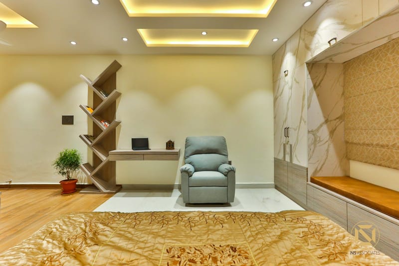 Bedroom seating area with grey recliner, angular zigzag shelf and recessed cove ceiling lighting, Hyderabad