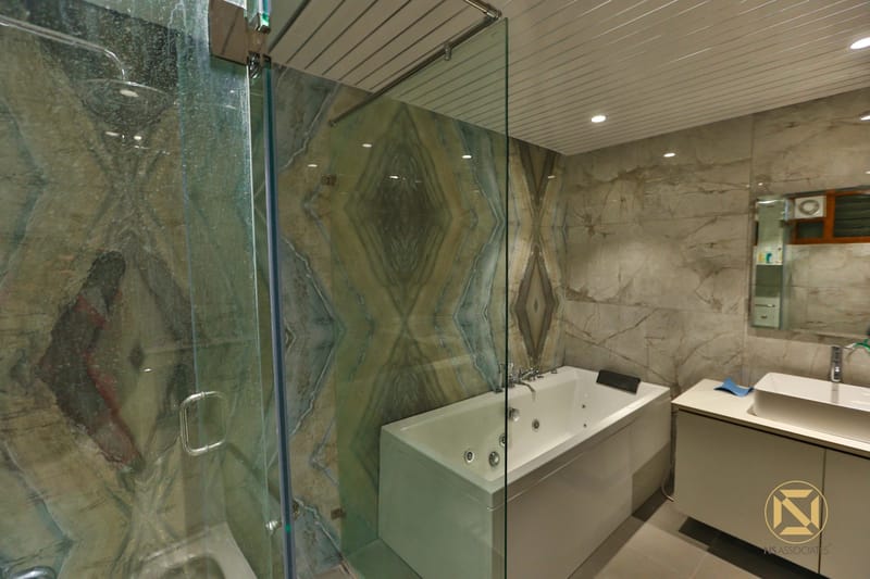Bathroom clad in onyx and grey marble with glass shower enclosure, white jacuzzi tub and floating vanity, Hyderabad