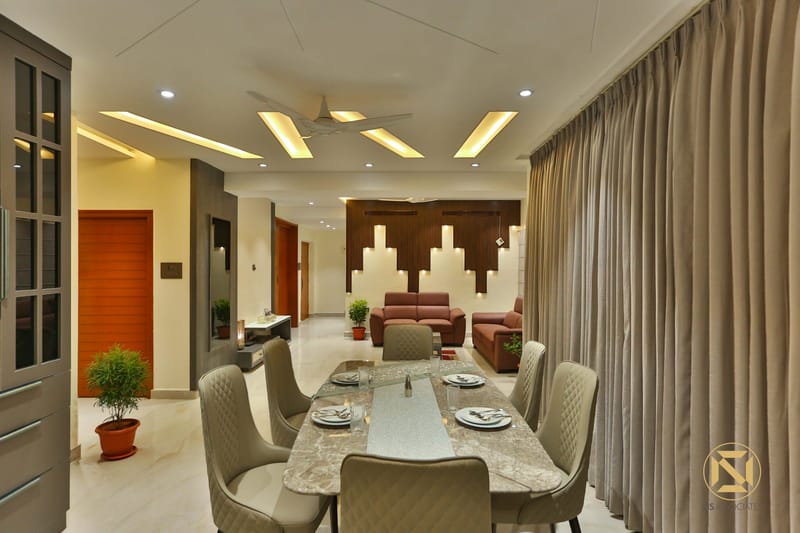 Dining room with marble-top table, quilted chairs and floor-length drapes opening to the living area beyond
